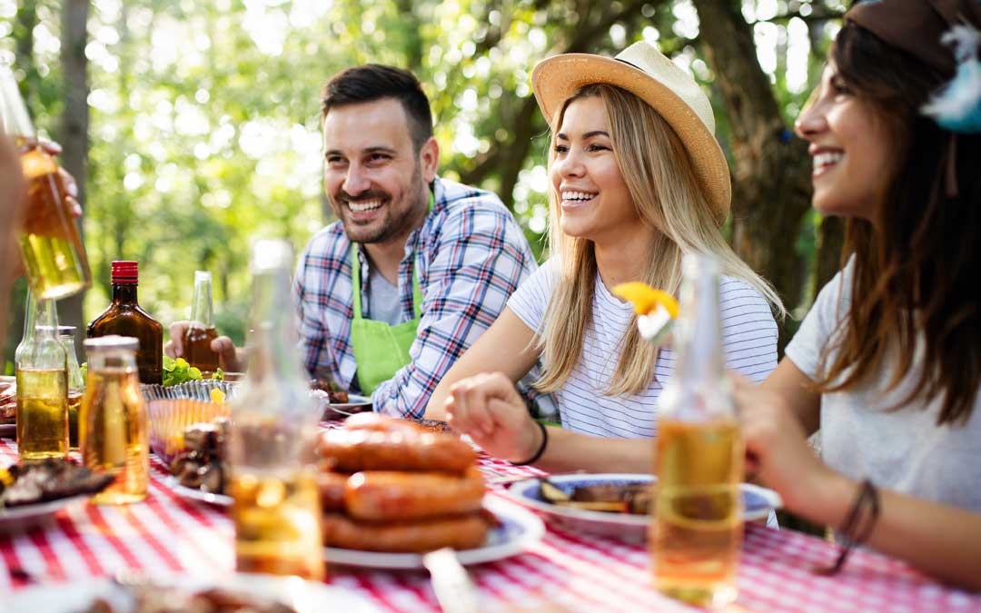 Group of happy friends eating and drinking at a barbecue dinner